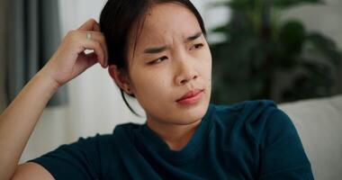 Handheld shot, woman sitting alone on the sofa thinking about life problems with a stressed expression. video