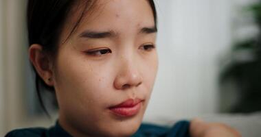 Handheld selective focus shot, Asian woman sitting alone on the sofa thinking about life problems with a stressed expression on her face. video