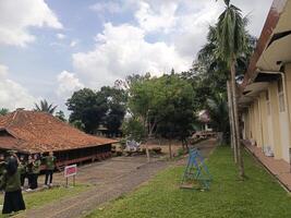 Outdoor Scene with Building, Students, Greenery, and Cloudy Sky photo
