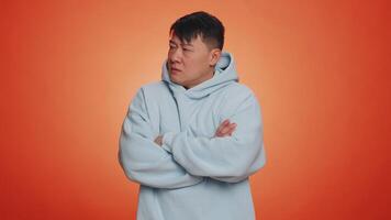 Offended sad nervous asian man having misunderstanding, frustrated after quarrel, fail, lose, ignores and does not want to communicate, talk. Guy isolated on orange studio background. People lifestyle video