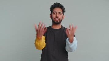 What Why. Sincere irritated indian man raising hands in indignant expression asking reason of failure demonstrating disbelief irritation by trouble. Handsome confused hindu guy on gray background video