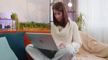 Displeased woman use laptop notebook typing browsing working, loses becoming surprised sudden lottery results bad news fortune loss fail computer virus. Portrait of girl at home in room on couch video