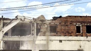 Powerful excavator demolishes a partially destroyed old building, clearing the site for future construction. Scene symbolizes renewal, war aftermath, or city transformation after destruction. video
