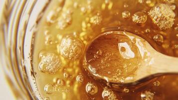 Close up view of honey with a wooden spoon inside a glass container photo