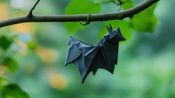 A paper origami bat hangs from a small tree branch photo