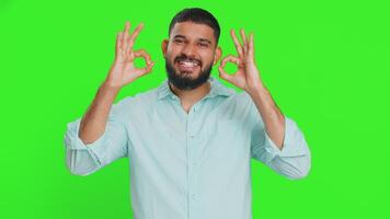 Okay. Happy Indian man looking approvingly at camera showing ok gesture, like sign positive feedback, approve something good, celebrate victory. Arabian guy isolated on green chroma key background video
