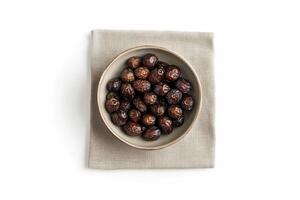 A bowl of dates rests on a beige linen napkin photo