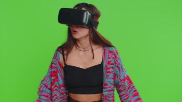 Woman using virtual reality futuristic technology VR app headset helmet to play simulation 3D 360 game, watching film movie. Excited hippie girl isolated on chroma key background, green screen video