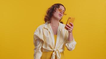 Woman use mobile phone smartphone typing browsing, loses becoming surprised sudden lottery results, bad fortune, loss, fail. Pretty brunette girl isolated alone on yellow studio background, indoors video