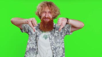 Dislike. Upset unhappy young man showing thumbs down sign gesture, expressing discontent, disapproval, dissatisfied, negative feedback. Attractive bearded guy indoors isolated on chroma key background video