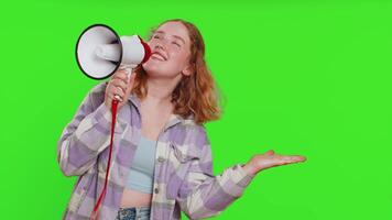 Happy caucasian woman talking with megaphone, proclaiming news, loudly announcing advertisement discounts sale, using loudspeaker to shout speech. Redhead girl isolated on green chroma key background video