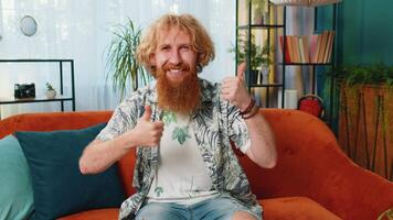 Like. Happy excited Caucasian man looking approvingly at camera showing thumbs up, like sign positive something, good great news, positive feedback. Young guy sitting on couch at home living room video