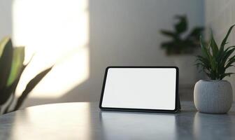 A tablet sits on a table next to a potted plant photo