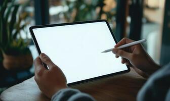 A person is holding a tablet and a pen, possibly writing or drawing on it photo