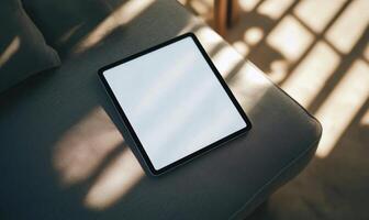 A tablet is sitting on a couch with a shadow on it photo