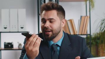 Bearded Caucasian businessman working, having mobile phone loudspeaker talk at office desk with laptop. Manager freelance happy man holding smartphone using messenger chat apps. Employment, occupation video
