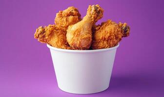 A bowl of fried chicken is sitting on a purple background photo