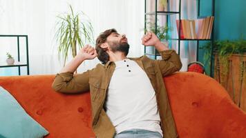 Tired middle eastern arabian man lying down in bed taking a rest at home. Carefree young bearded guy napping, falling asleep on comfortable sofa couch with pillows. Closed eyes enjoy daytime nap alone video