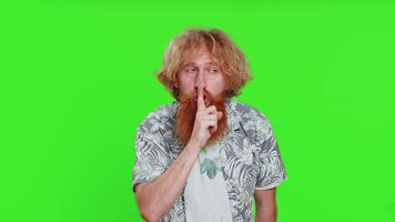Shh be quiet please. Young man presses index finger to lips makes silence gesture sign do not tells secret, stop talk gossip confidential privacy. Redhead bearded guy isolated on chroma key background video