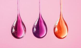 Three drops of liquid with different colors are hanging from a surface photo