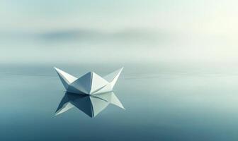 A paper boat sits in the water, reflecting the sky above photo