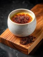 Creme brulee in a speckled ceramic ramekin, close up image on wooden board. photo