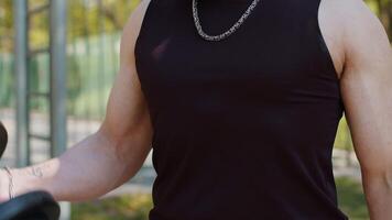 Close-up athletic man in sportswear doing arms weight lifting dumbbells exercises, pumping up arm bicep muscles. Guy on playground. Sports, fitness routine, bodybuilding workout. Strength motivation video