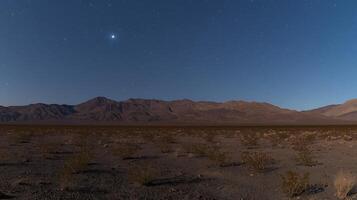 Night Sky over Desert Landscape with Mountain Range. A serene image of stars shining brightly over a vast desert plain and distant mountains. photo