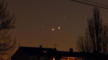 Night sky over suburban rooftops with visible planets and stars. A captivating astronomical scene. photo