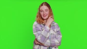 Smiling playful happy young caucasian woman blinking eye, looking at camera with smile, winking, flirting, expressing optimism, good news. Charming redhead girl isolated on green chroma key background video