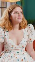 Portrait of happy calm young redhead woman at home couch smiling friendly glad expression looking dreaming resting, relaxation feel satisfied concept good news, celebrate win. Girl in room. Vertical video