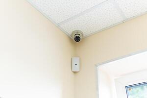 Security camera and motion detector installed on ceiling in room. photo
