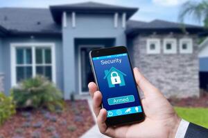 Smartphone with home security app in a hand on the building background. photo