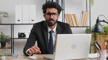 I choose you. Young indian businessman programmer software developer working on office laptop pointing to camera, looking with happy expression, making choice, showing direction. Arab freelancer man video