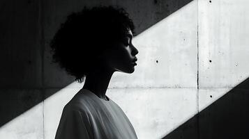 Silhouette of a Woman in Profile Against a Concrete Wall. A striking black and white image showcasing light and shadow. photo