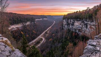 Scenic Autumn Sunset Over a Winding Road in a Deep Gorge. A breathtaking panoramic view of fall foliage and a highway nestled between towering cliffs. photo