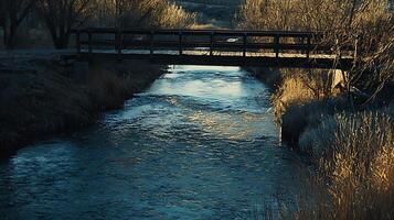 Wooden Footbridge Over a Gently Flowing Stream at Sunset. A tranquil scene of nature's beauty. photo