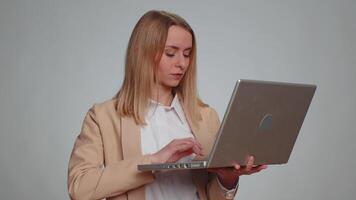 Excited happy business woman typing on laptop computer, working on project, enjoying results, winning lottery, celebrating success, online shopping. Girl in formal suit isolated on gray background video