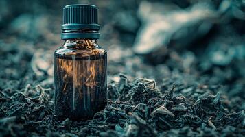 Amber Bottle of Essential Oil Resting on Dried Tea Leaves. A close up image of a small glass bottle with a black cap. photo