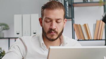 Close-up portrait bearded businessman face freelancer at home office workplace working on laptop computer. Manager freelancer middle eastern man works on notebook send messages makes online purchases video
