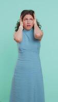 Dont want to hear and listen. Frustrated annoyed irritated woman covering ears gesturing No, avoiding advice ignoring unpleasant noise loud voices. Girl isolated alone on blue background. Vertical video