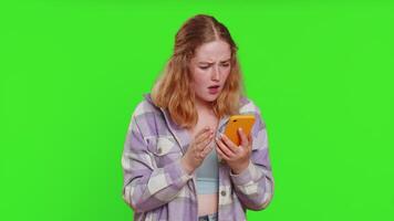 Upset sad woman use smartphone typing browsing, play game, loses, surprised by sudden lottery results bad fortune loss fail unlucky news. Sad redhead girl isolated on chroma key background, indoors video