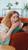 Happy woman use mobile smartphone typing browsing say Wow yes found out great big win good news celebrate lottery jackpot, play victory game. Redhead girl at home in room lying on sofa. Vertical shot video