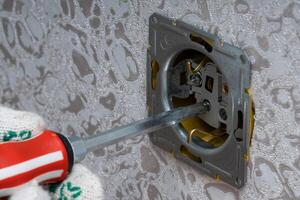 An electrician safely works with switches and sockets of a household electrical system photo