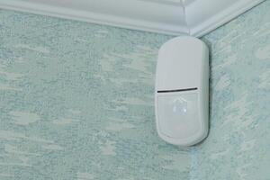 Modern white motion sensor on the wall in the room. photo
