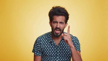 Quarrel. Displeased young indian man gesturing hands with irritation and displeasure, blaming scolding for failure, asking why this happened. Bearded hindu guy isolated on yellow studio background video