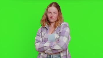 Funny comical playful young woman making silly facial expressions and grimacing, fooling around, showing tongue, idiotic expression. Girl isolated on green chroma key background. People lifestyles video