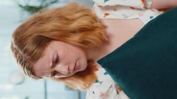 Young upset redhead woman looking with rage aggression, scolding protest, fighting with pillow to camera, bad news, displeasure, quarrel, play game. Sad Caucasian girl at home room apartment. Vertical video