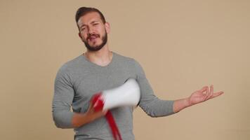 Lebanese young man talking with megaphone, proclaiming news, loudly announcing advertisement, warning using loudspeaker to shout speech, sale. Middle eastern guy isolated on beige studio background video