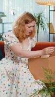 Angry dissatisfied shopper young woman unpacking parcel feeling upset and confused with the wrong delivery from an online store, bad quality purchase at home. Girl indoors in room on couch. Vertical video